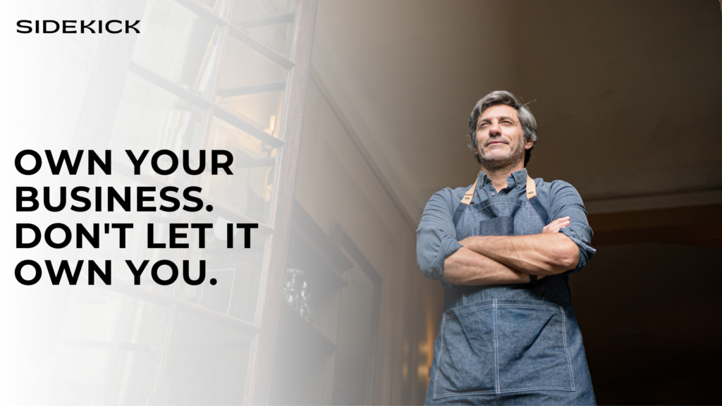 Confident man in a denim apron standing in a doorway with arms crossed, looking proud. Text reads: ‘Own your business. Don’t let it own you.’ with Sidekick logo